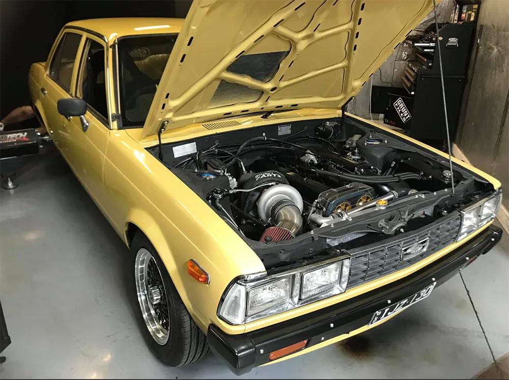 Pale-yellow car with its bonnet open inside the Cleveland Dyno workshop
